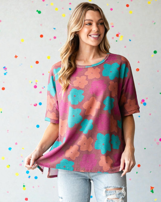 Woman wearing a colorful floral-patterned shirt against a polka dot background