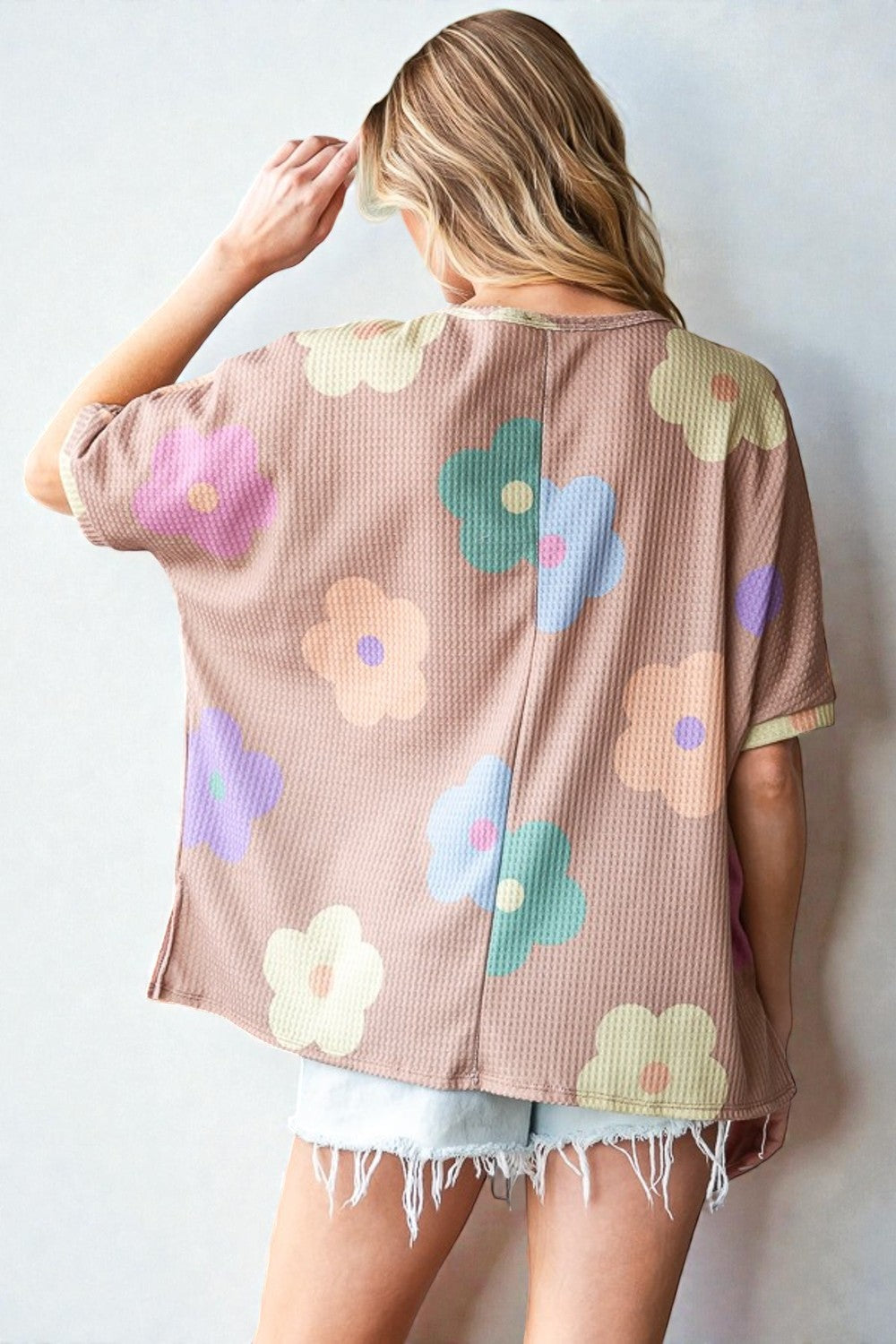 Woman wearing a beige cardigan with colorful floral patterns on a white background