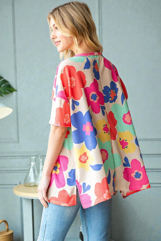 Woman wearing a colorful floral kimono against a light gray wall.