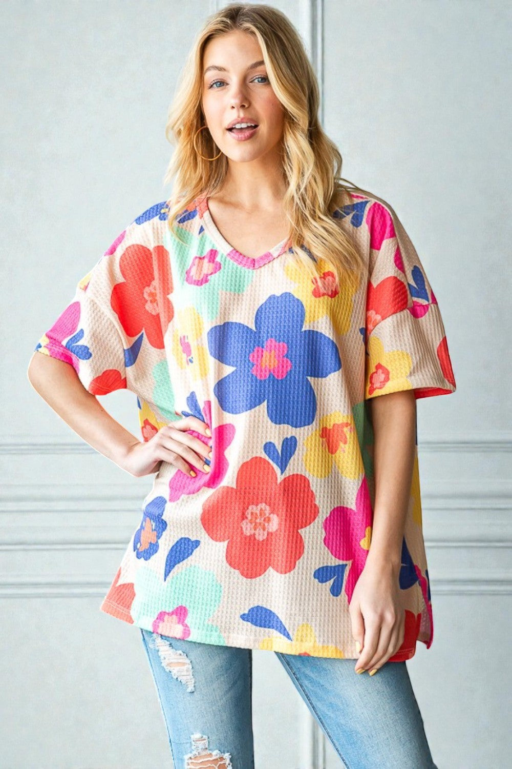 Woman wearing a colorful floral top against a light gray background