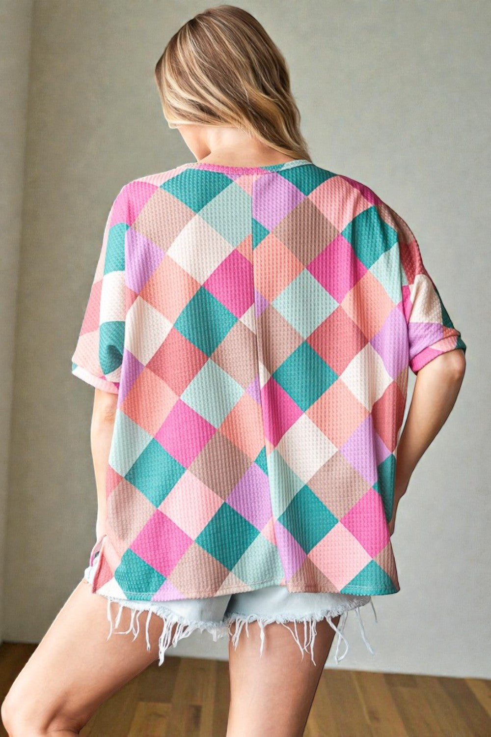 Woman wearing a colorful checkered shirt with a neutral background