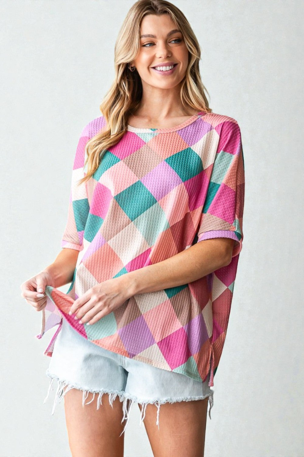 Woman wearing a colorful checkered top with a plain background