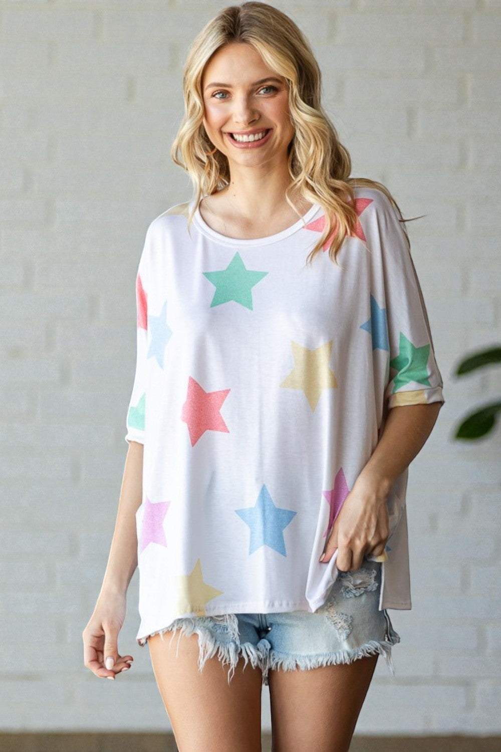 Woman wearing a white t-shirt with colorful star patterns against a light background