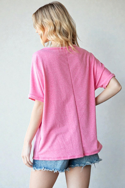 Person wearing a pink t-shirt and denim shorts against a plain background