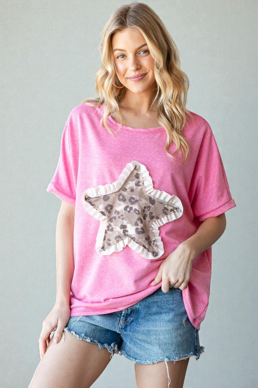 Woman wearing a pink t-shirt with a star design, standing against a plain background