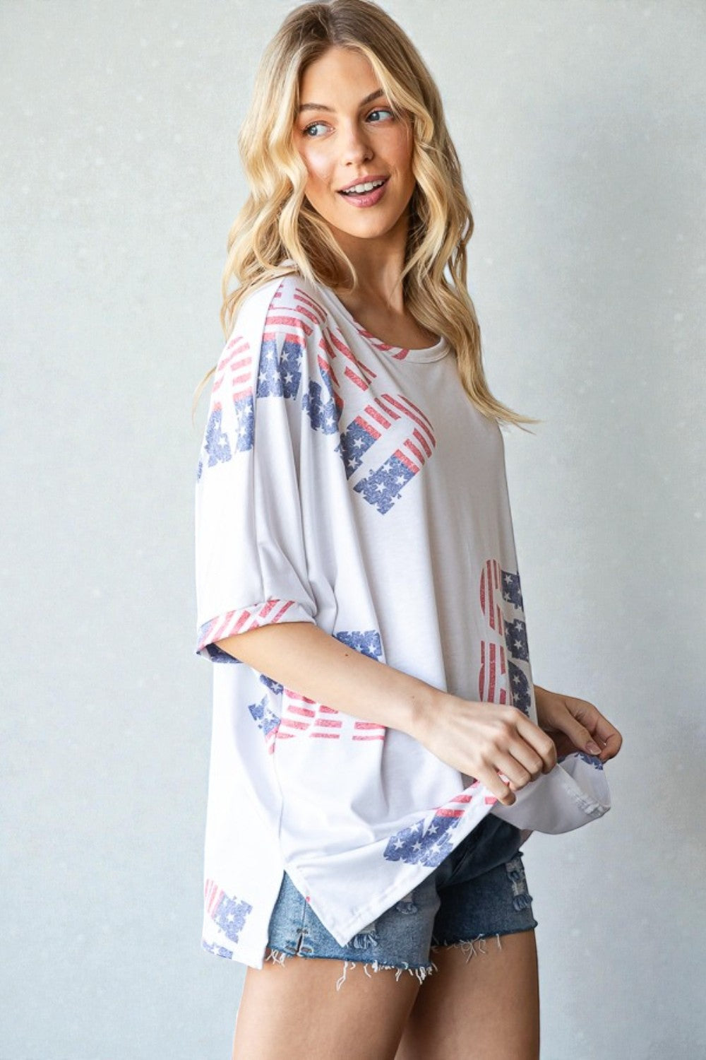 Woman wearing a white top with red, white, and blue pattern against a plain background