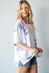 Woman wearing a white top with red, white, and blue pattern against a plain background
