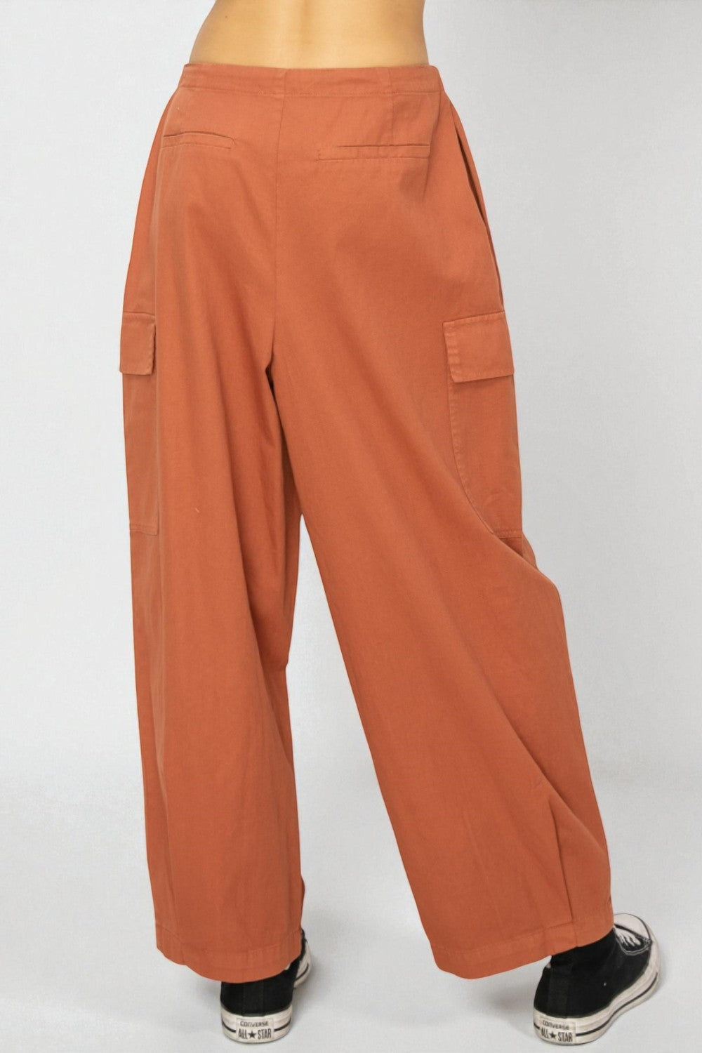 Orange wide-leg pants worn by a person on a white background