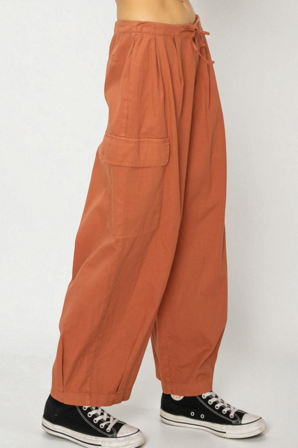 Orange wide-leg pants worn by a person on a white background