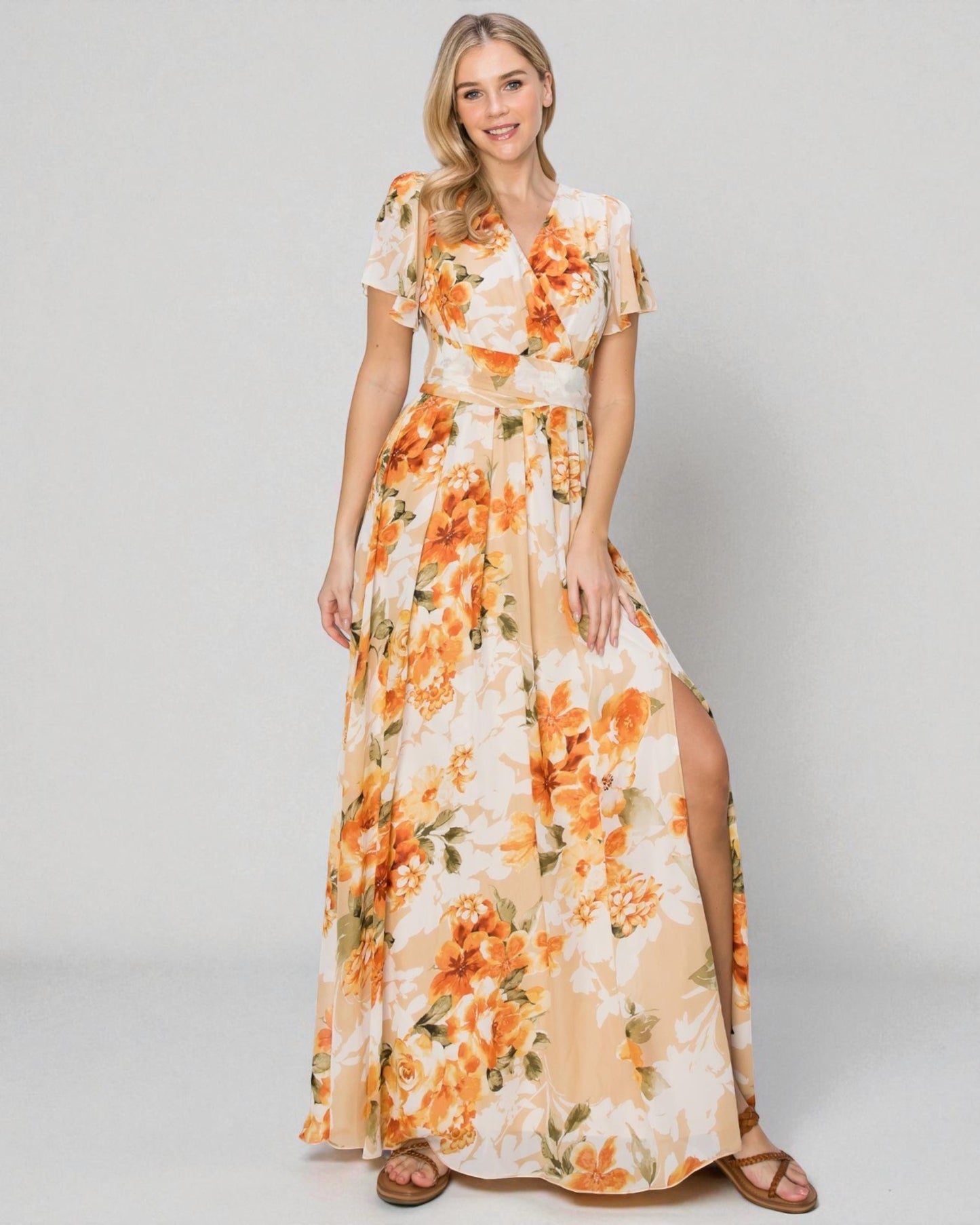 Woman wearing a floral dress with orange flowers on a plain background