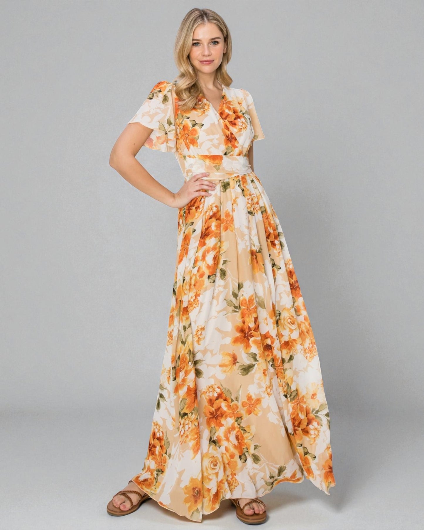 Woman wearing a floral dress with orange and yellow flowers on a gray background