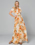 Woman wearing a floral dress with orange and yellow flowers on a gray background