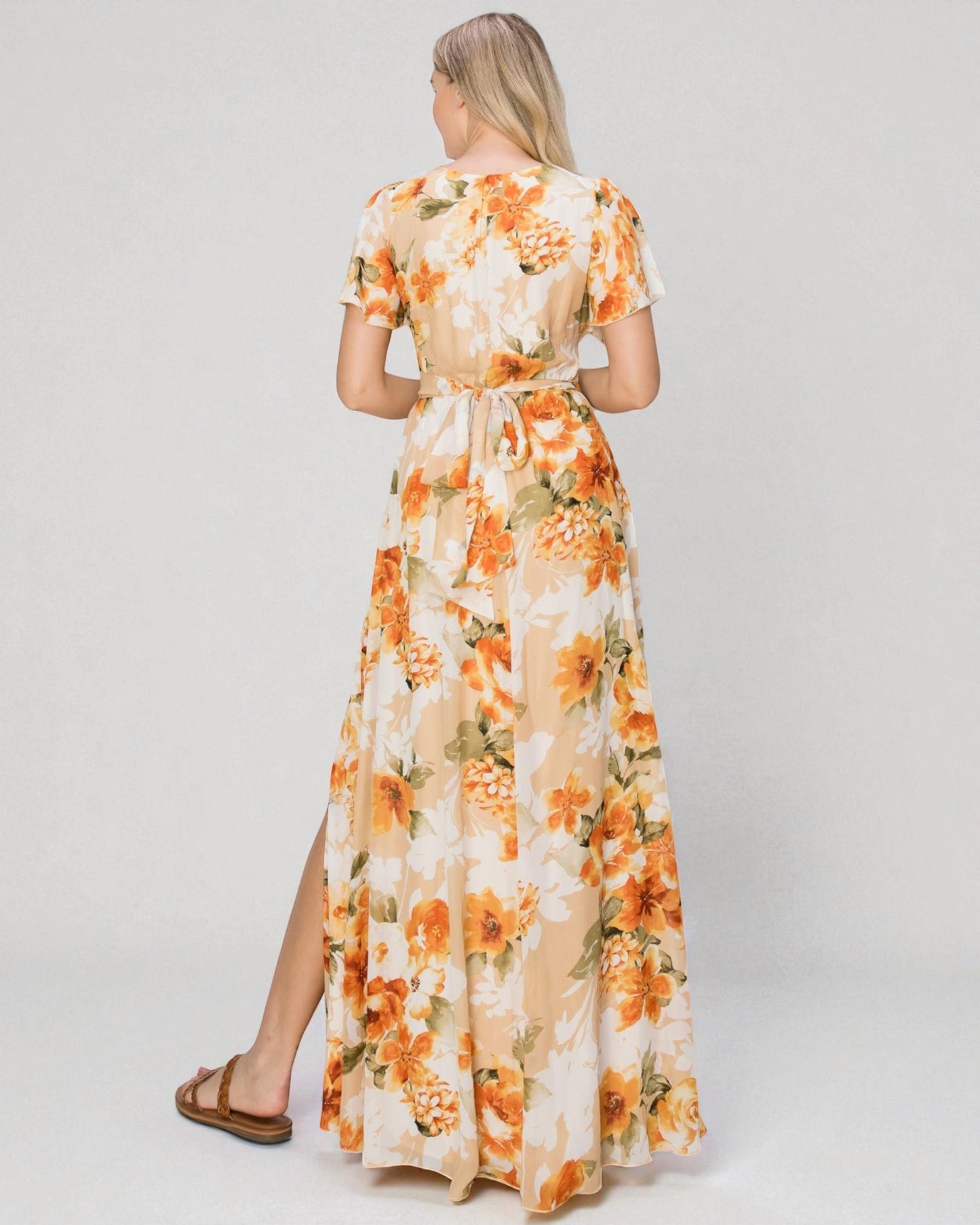 Woman wearing a floral dress with orange flowers on a plain background