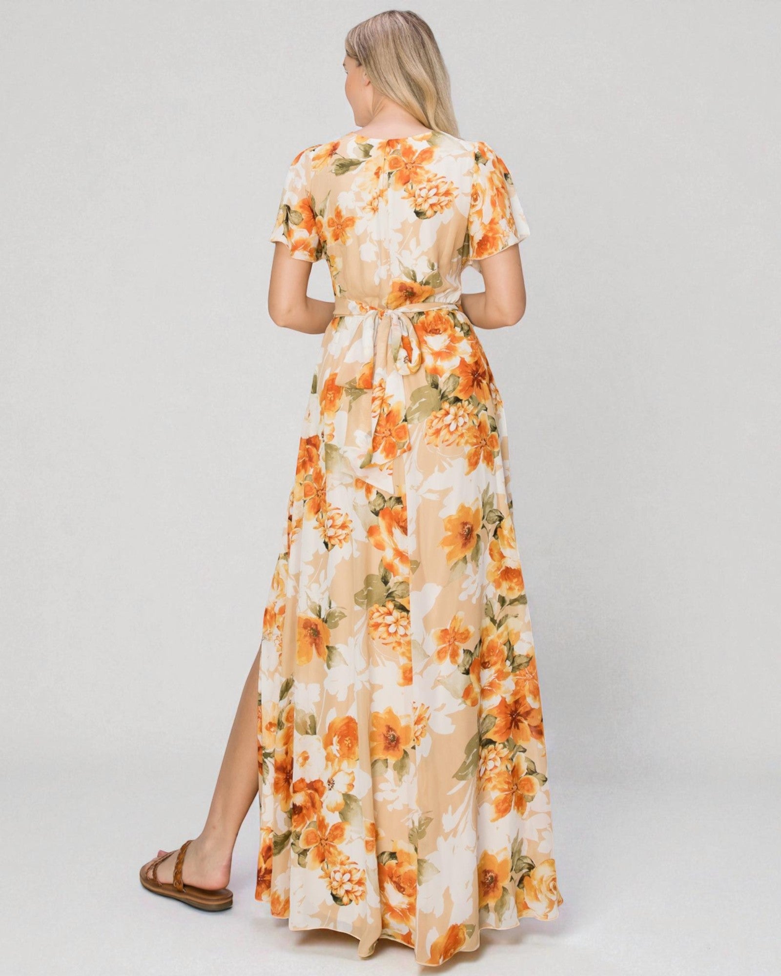 Woman wearing a floral dress with orange flowers on a plain background