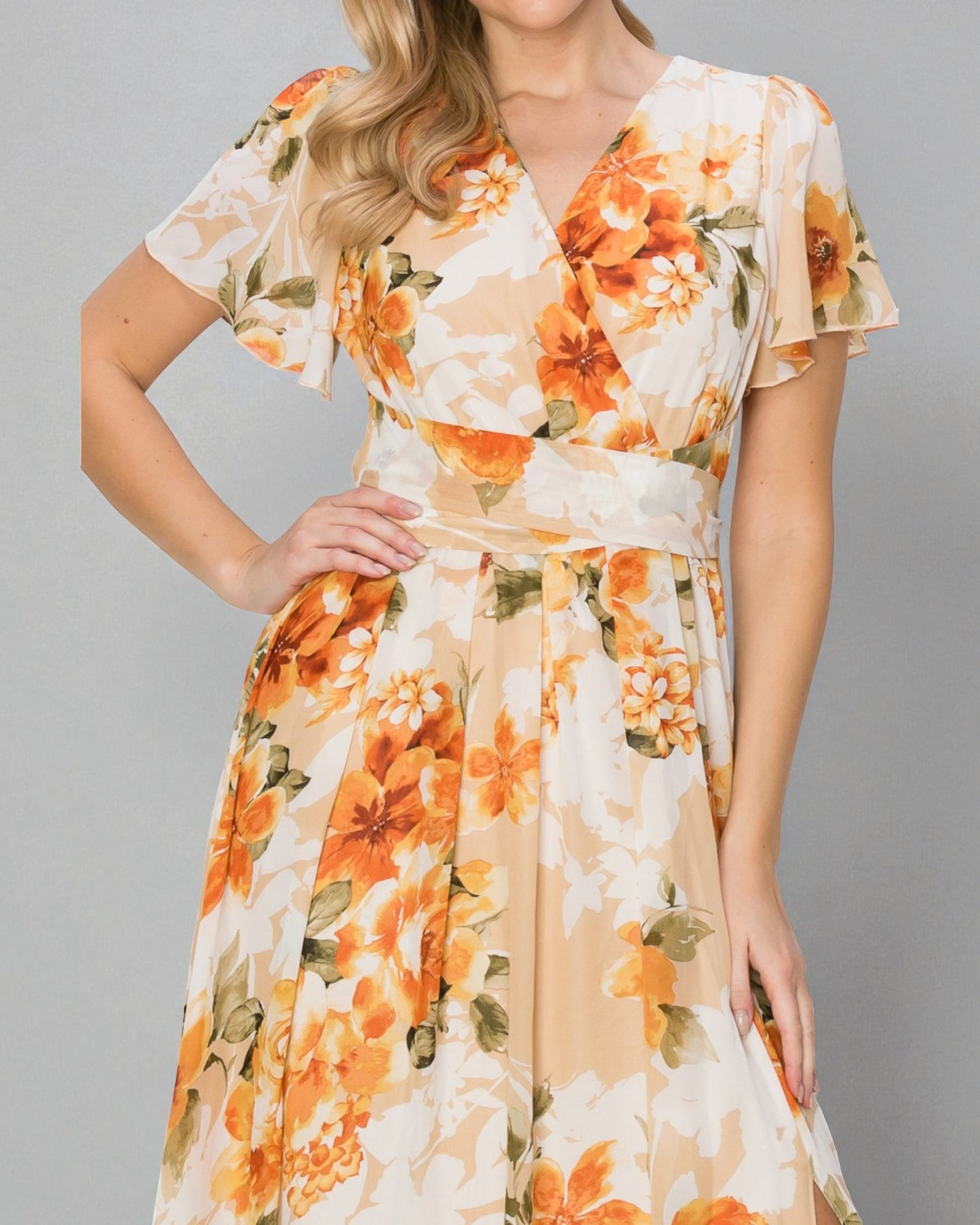 Woman wearing a floral dress with orange and green flowers on a gray background
