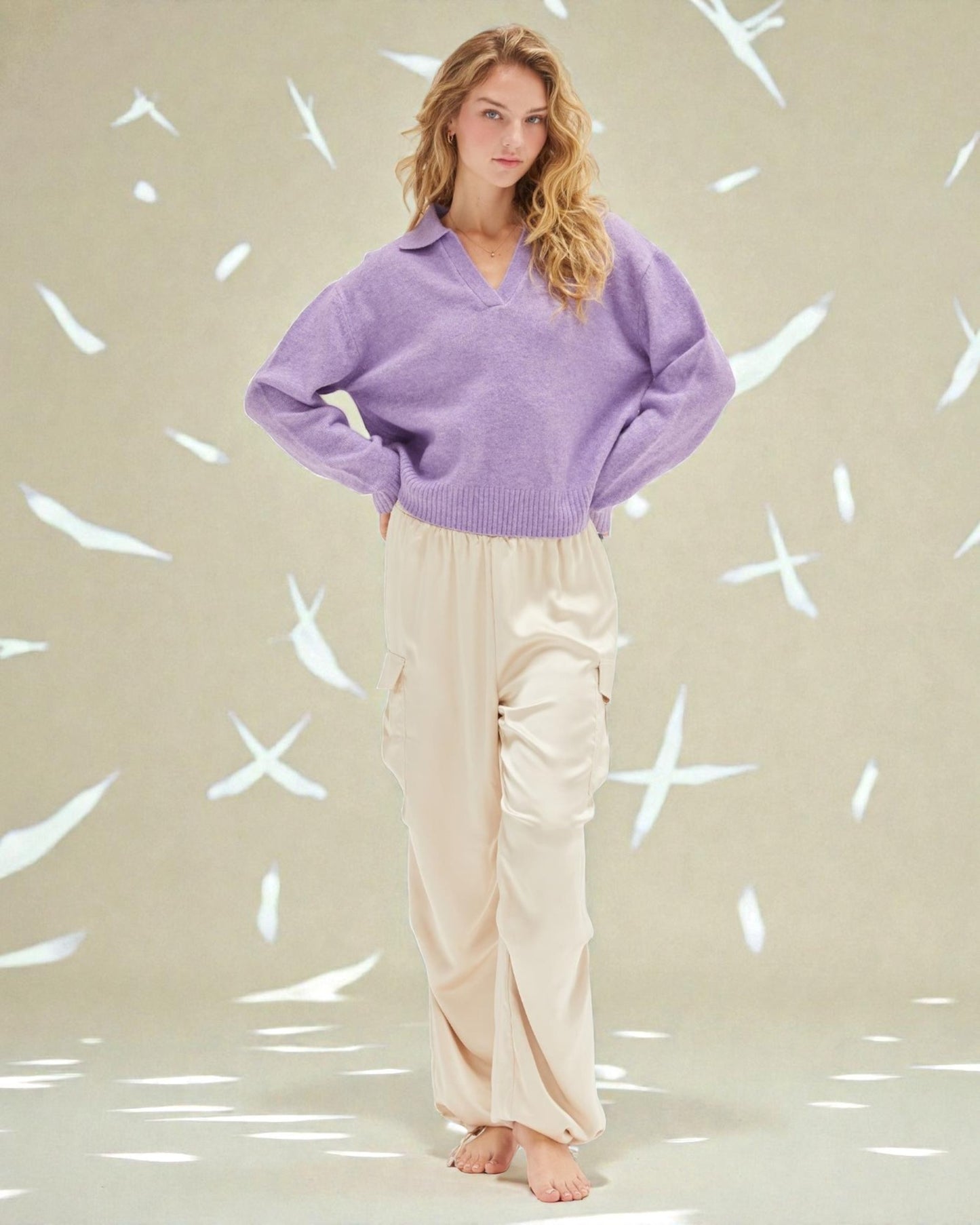 Woman wearing a purple sweater and beige pants against a light background