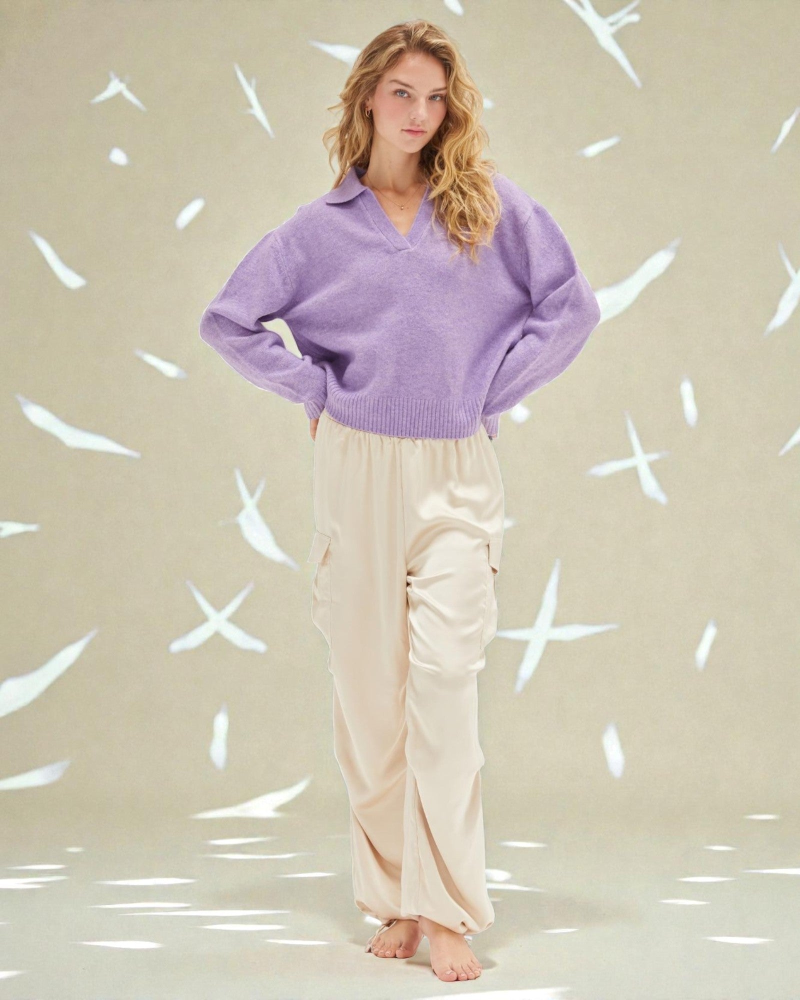Woman wearing a purple sweater and beige pants against a light background