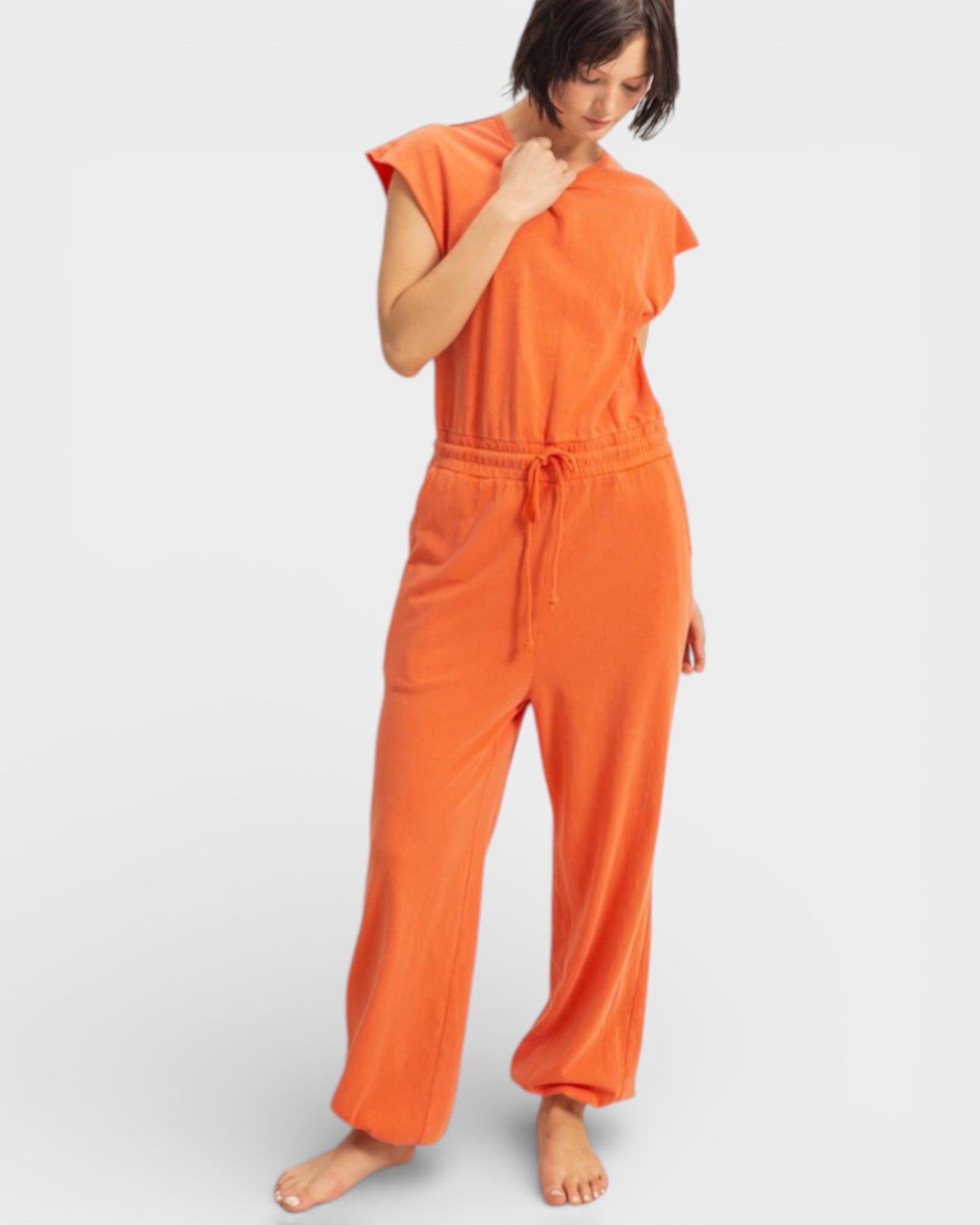 Woman wearing an orange jumpsuit on a white background