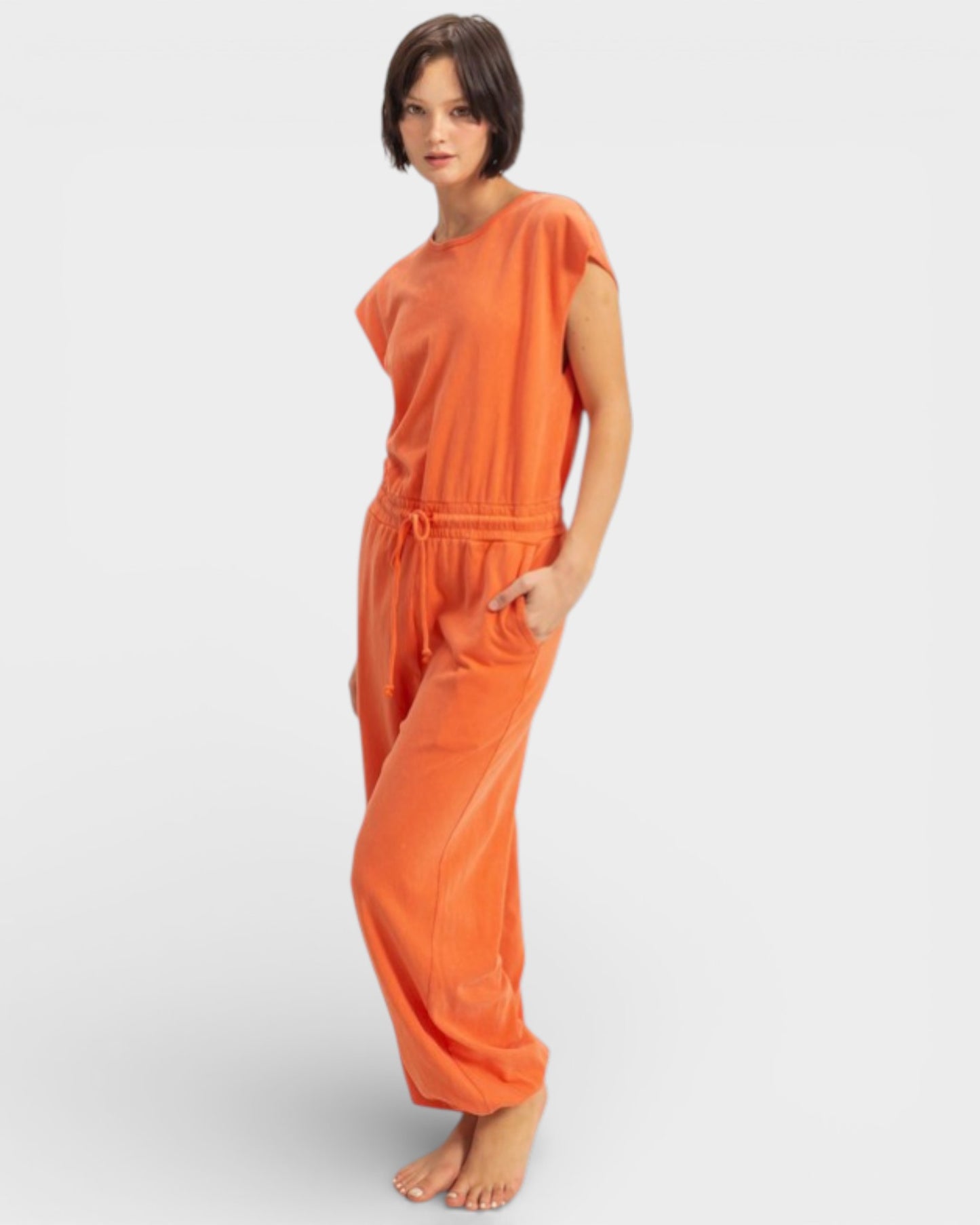 Woman wearing an orange jumpsuit on a light gray background