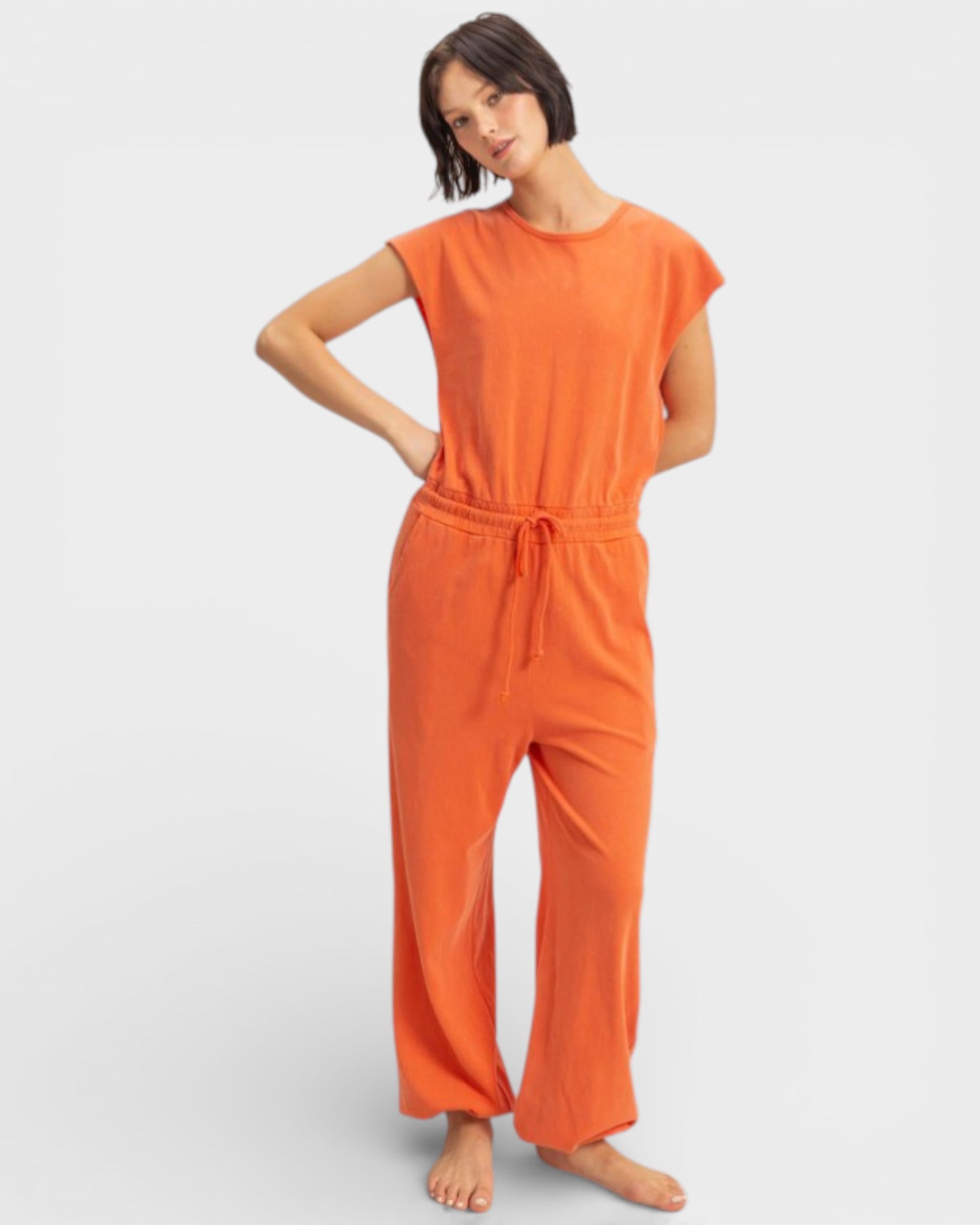 Woman wearing an orange jumpsuit on a plain background