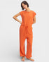 Woman wearing an orange jumpsuit on a plain background