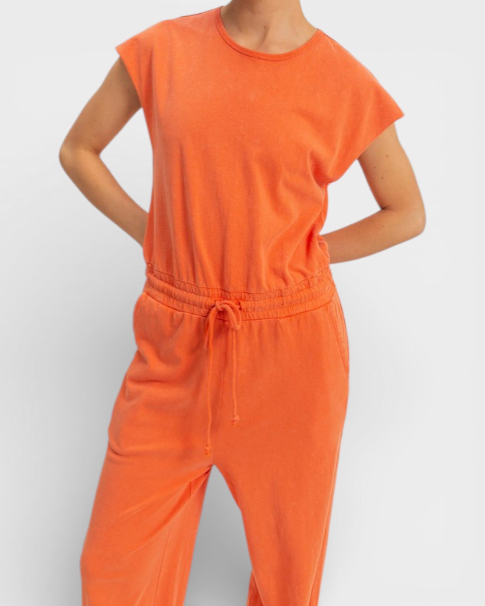 Person wearing an orange jumpsuit on a plain background