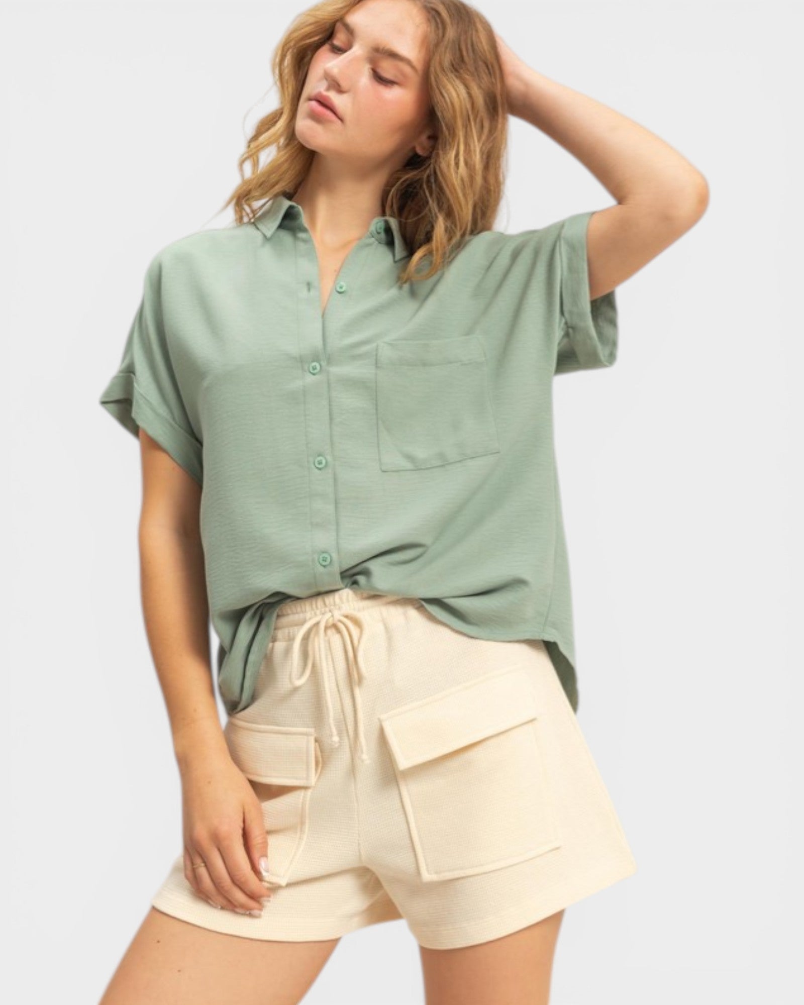 Woman wearing a green shirt and beige shorts on a white background