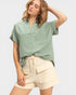 Woman wearing a green shirt and beige shorts on a white background