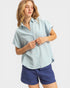Woman wearing a light blue shirt and navy shorts on a white background