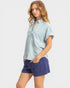 Woman wearing a light blue shirt and navy shorts on a white background