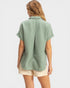Woman wearing a green shirt and beige shorts on a white background