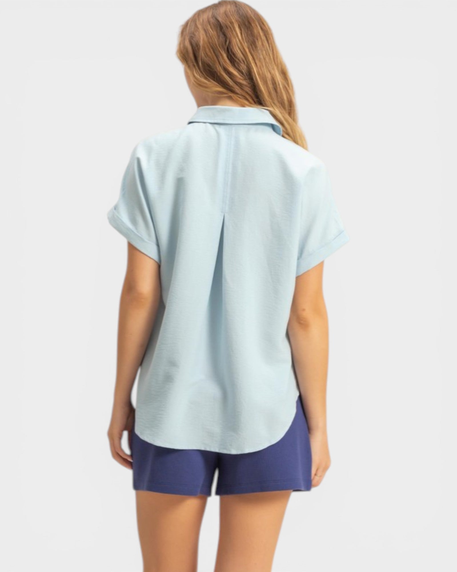 Woman wearing a light blue shirt and navy shorts on a white background