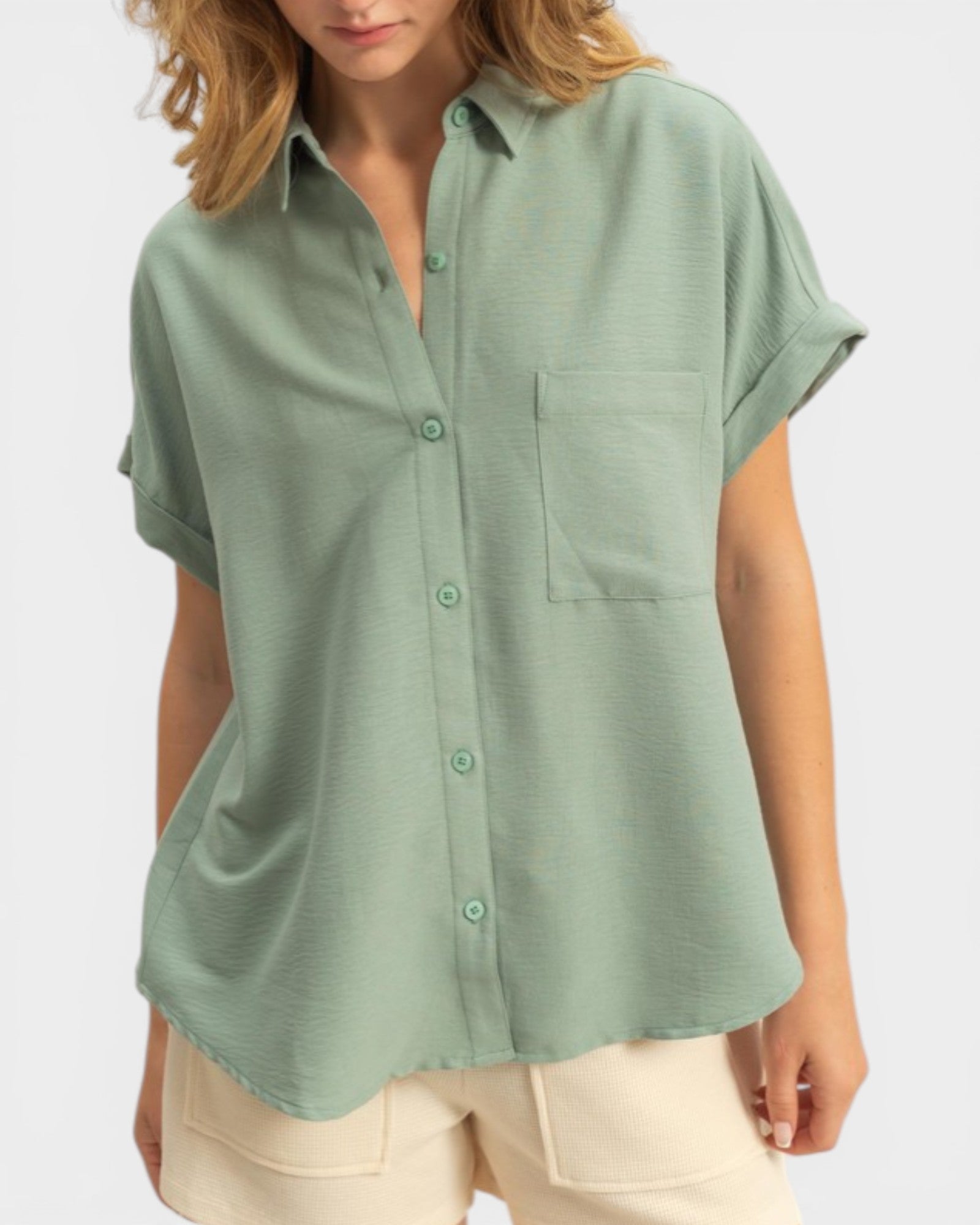 Person wearing a green button-up shirt with a pocket on a white background