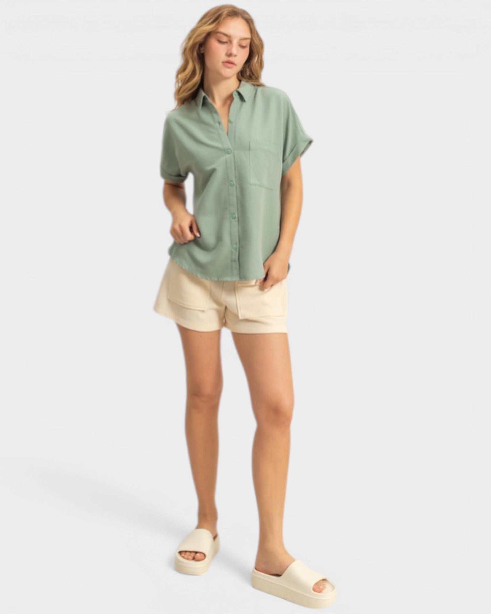 Woman wearing a green shirt and beige shorts on a white background