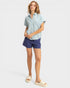 Woman wearing a light blue shirt and blue shorts on a white background