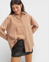 Woman wearing a beige shirt and black leather skirt on a white background