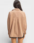 Person wearing a beige jacket on a plain background