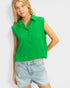 Woman wearing a green sleeveless shirt and denim shorts on a white background