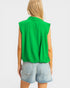 Person wearing a green sleeveless top and denim shorts on a white background