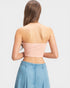 Woman wearing a strapless pink top and denim skirt on a light gray background