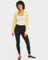 Woman wearing a yellow cardigan, white top, and black leggings on a white background