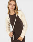 Woman wearing a cream cardigan over a brown dress on a white background