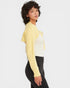 Woman wearing a yellow long-sleeve top with a white shirt underneath on a white background