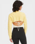 Person wearing a yellow long-sleeve top with cut-out design and black pants on a white background