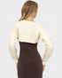 Woman wearing a cream cardigan over a brown dress on a plain background