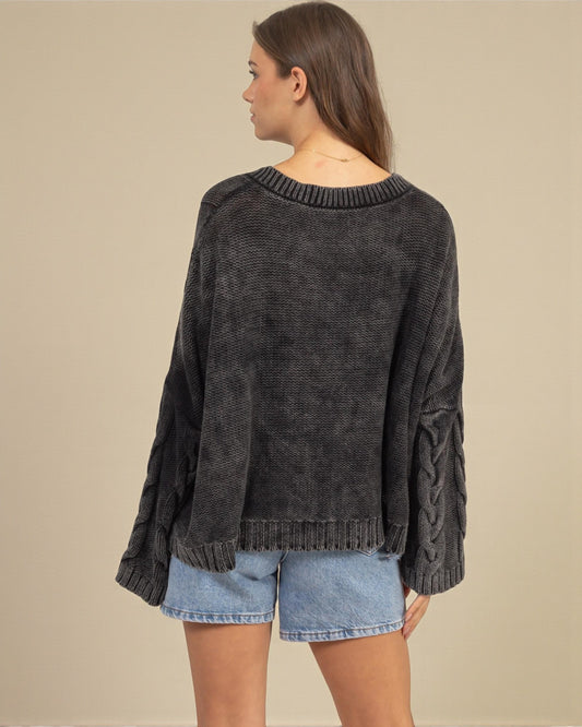 Woman wearing a dark gray sweater and denim shorts on a beige background