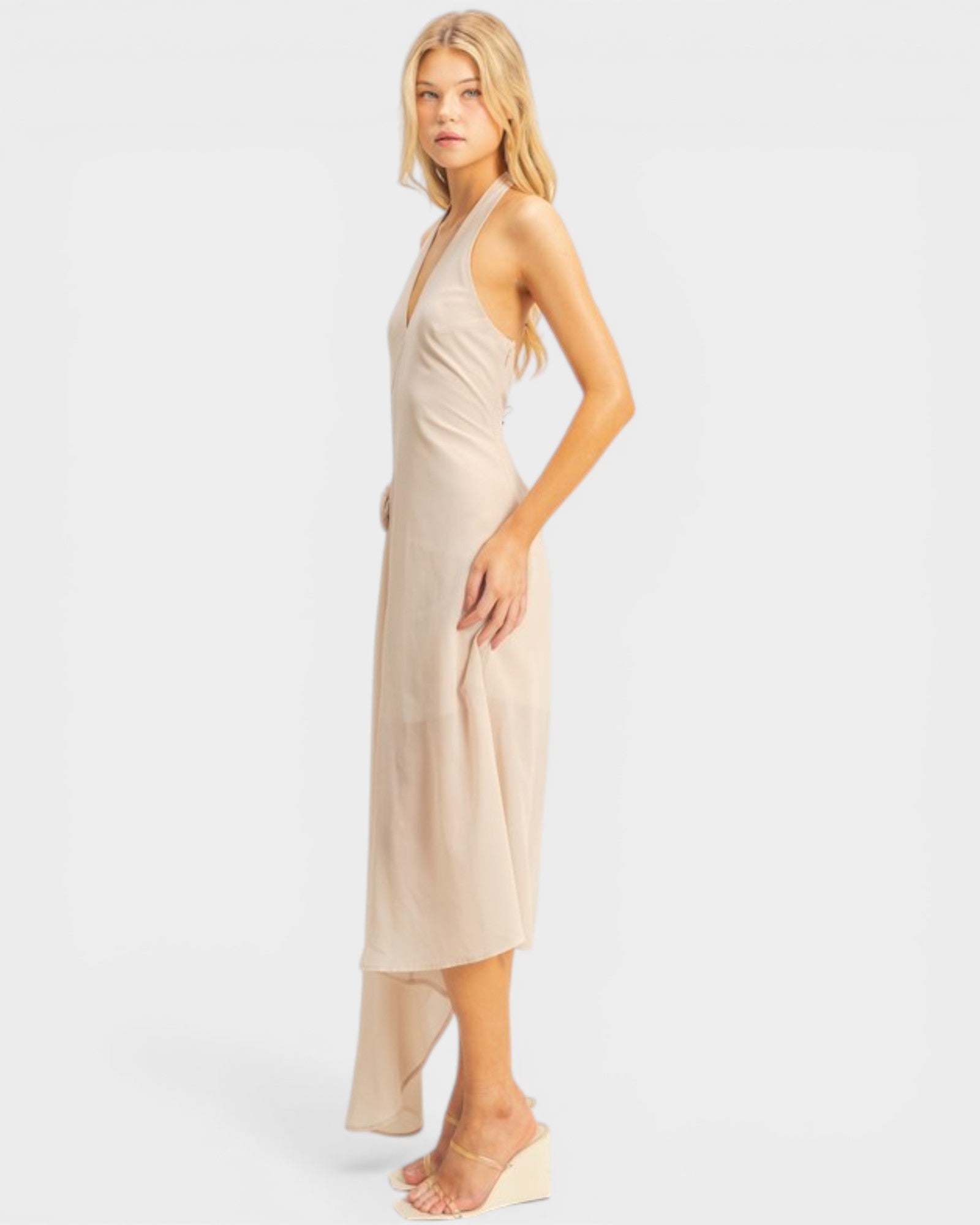 Woman wearing a beige halter neck dress on a white background