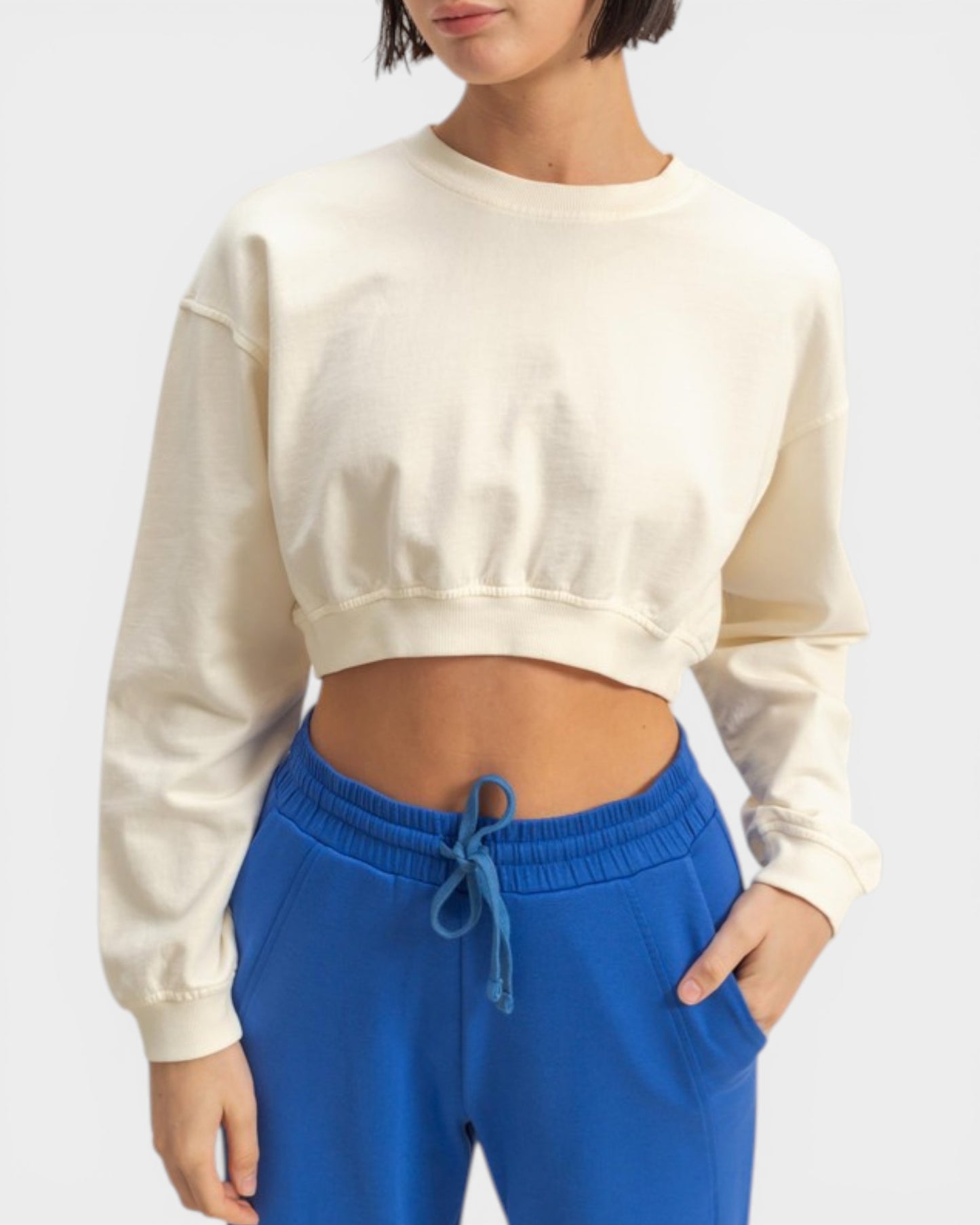 Person wearing a cream sweatshirt and blue pants on a white background