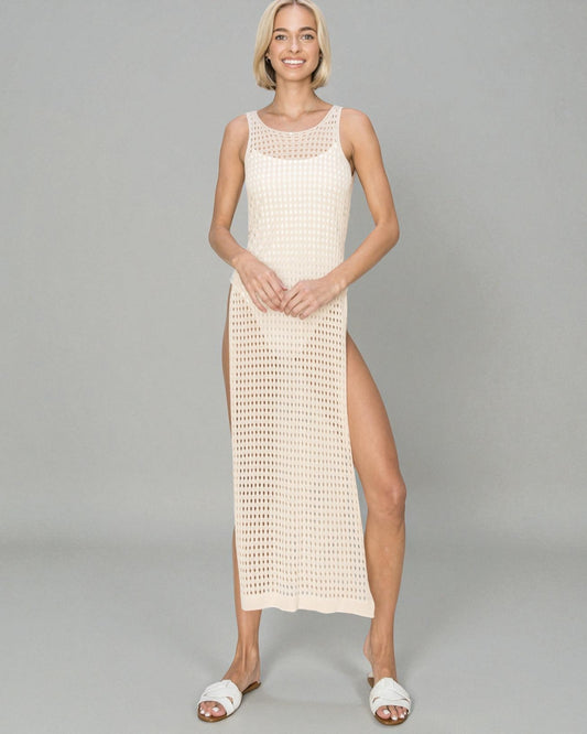 Woman wearing a beige crochet dress with a slit on a gray background