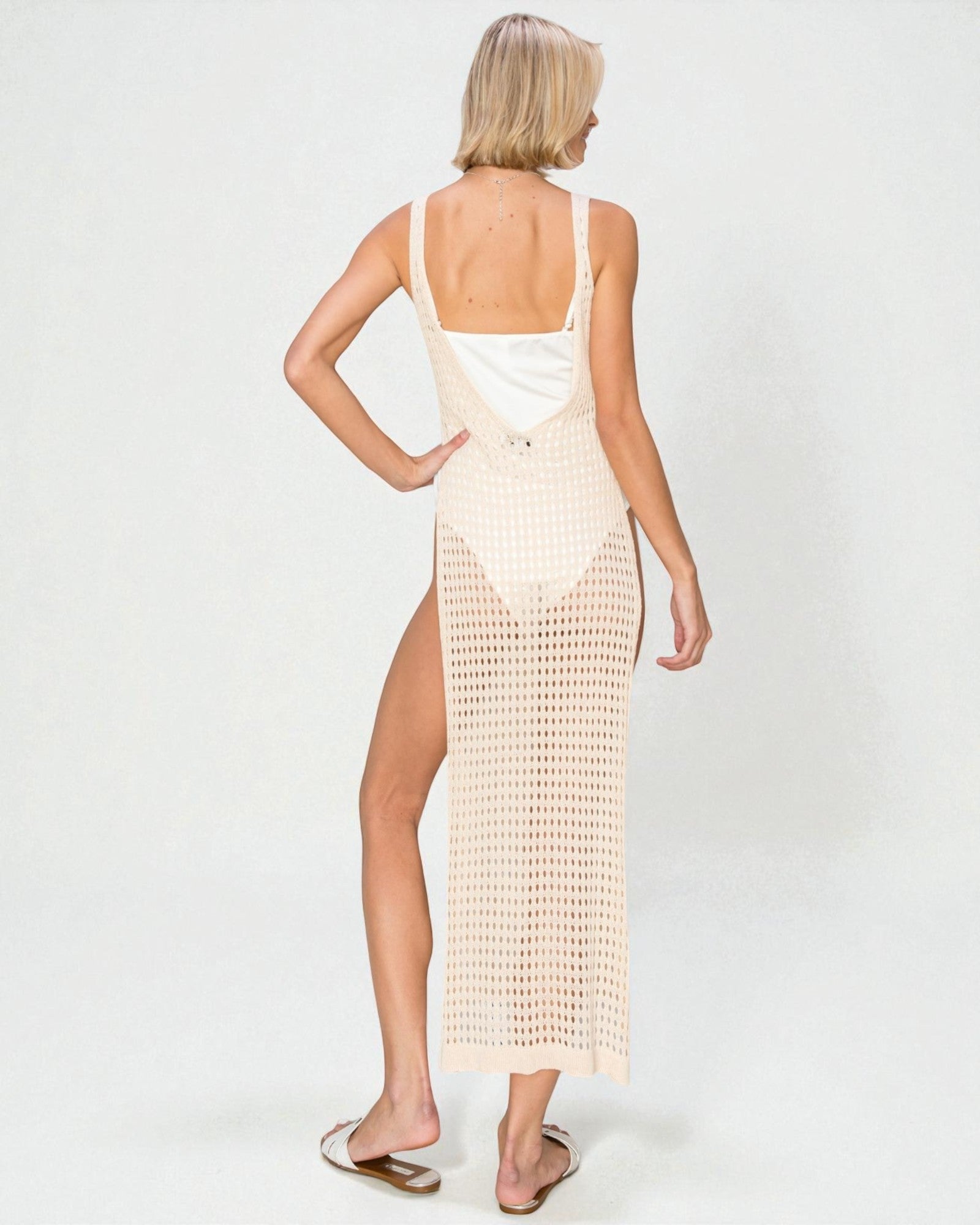 Woman wearing a beige crochet dress with a white top on a white background